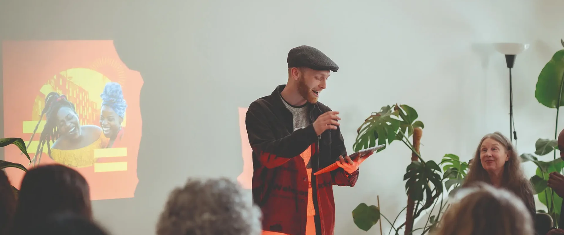 A man holding a tablet talks to seated crowd